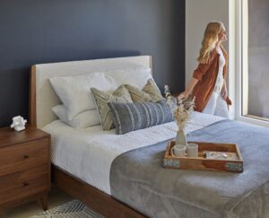 A bedroom after home improvement with a bed, table, rug and blue accent wall.