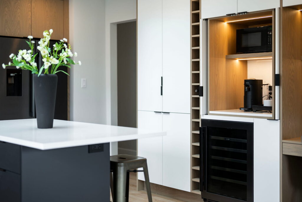 Modern kitchen with wood cabinetry, black island, and built-in wine cabinet