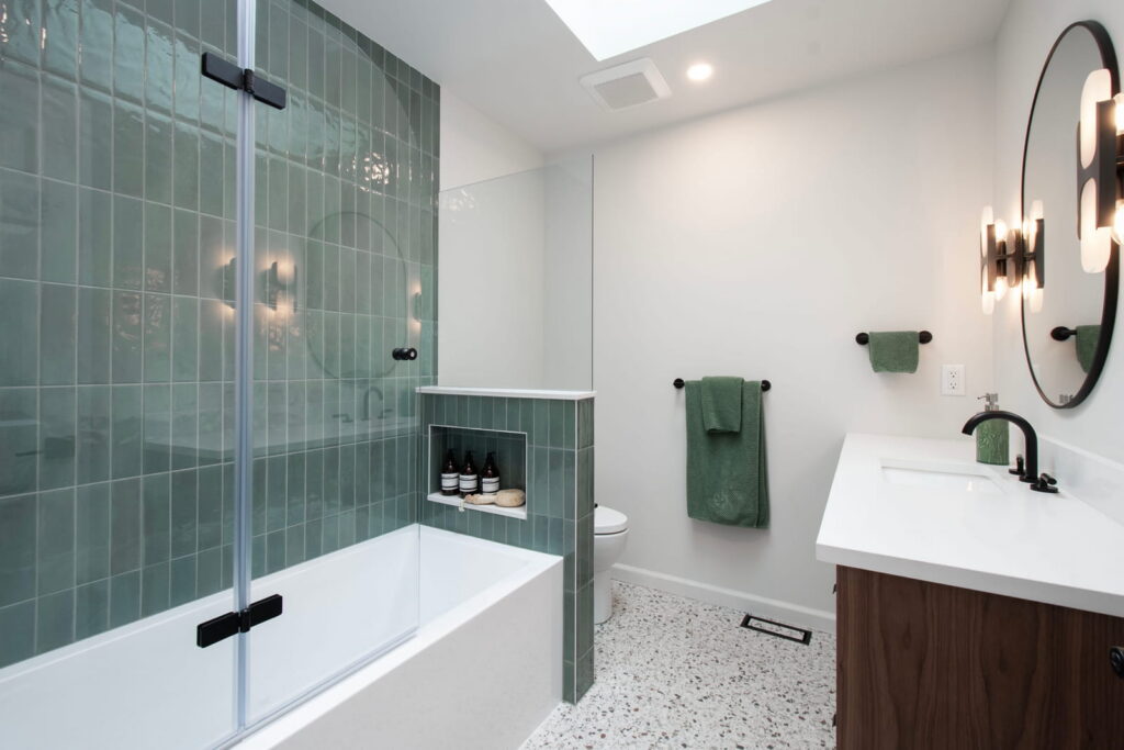 Modern bathroom with green tile, glass shower, and light tile walls