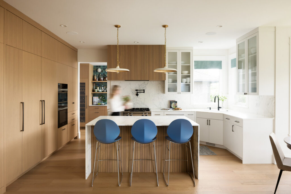 Modern award-winning kitchen in Coquitlam with marble island, blue stools and warm wood cabinetry